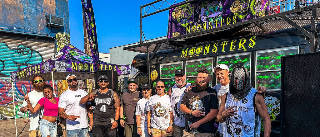 Group of people posing in front of a colorful truck with 'Monsters' branding.