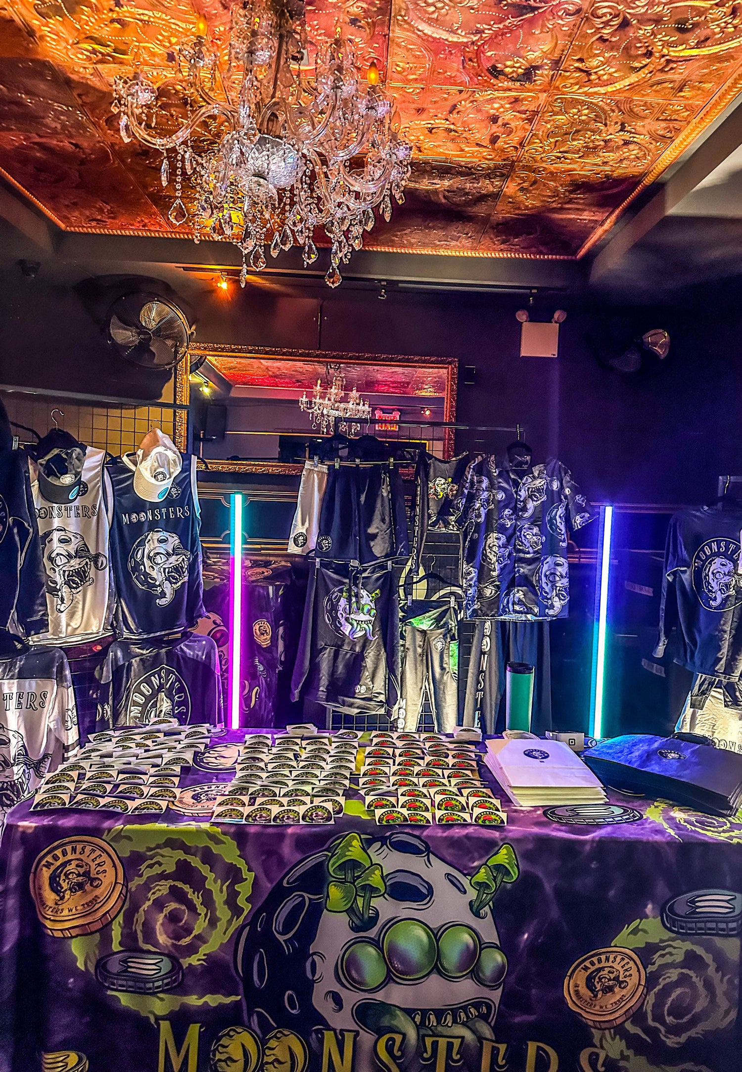 Display of Moonsters merchandise with a chandelier and colorful lighting in the background